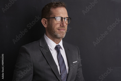 Senior lawyer portrait. Portrait shot of a middle aged businessman standing at dark background. 