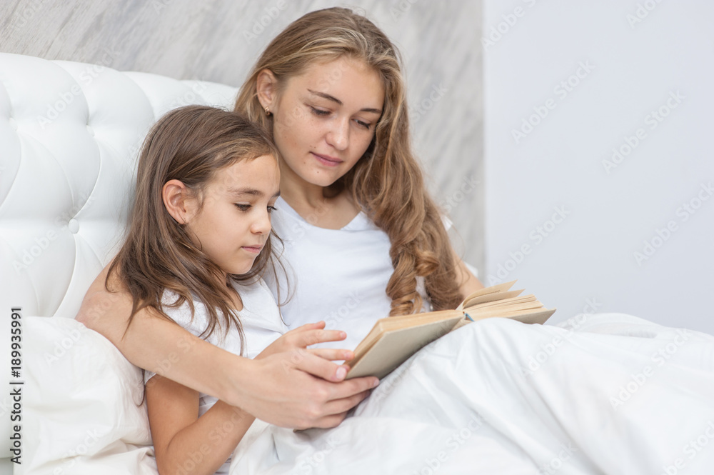 Mother and daughter reading a book on the bed Mother and daughter reading a book on the bed