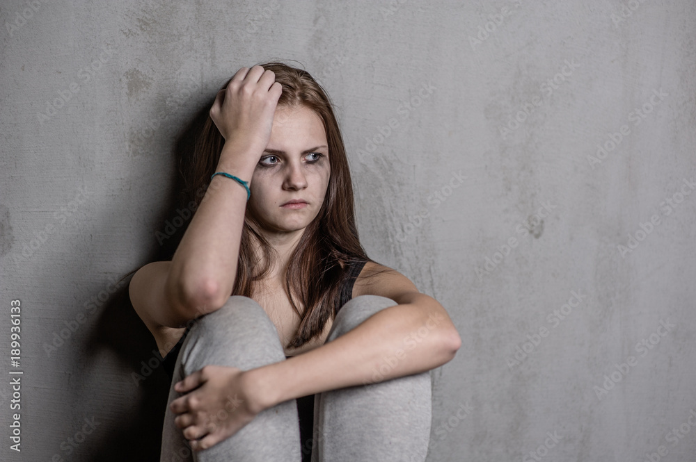 Fototapeta premium sad teen girl hug her knee and cry. Space for text