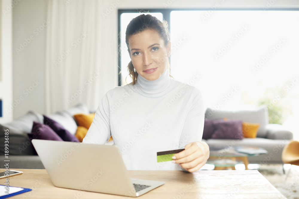 Shopping from home. Attractive woman using her laptop to make online purchases with her credit card while sitting at desk at home. Shopping from home. Attractive woman using her laptop to make online purchases with her credit card while sitting at desk at home.