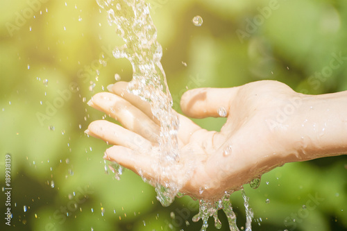 Woman washing hand outdoors. Natural drinking water in the palm. Young hands with water splash, selective focus