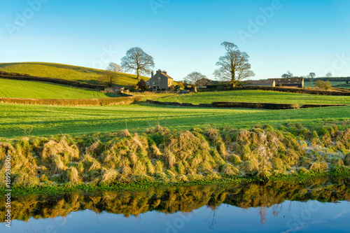 A view of the Lancaster canal with a farm house, bordered by two trees