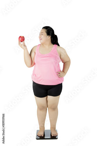 Fat woman with apple and weighing scale