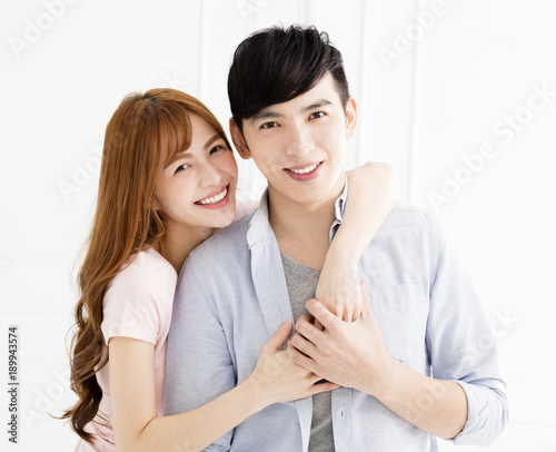 happy young asian couple hugging in living room