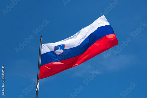Flag of Slovenia waving in wind, blue sky backdrop