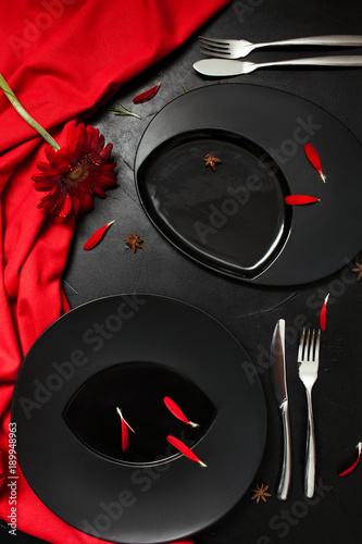 Matte plate on black background with red accent color. Creative restaurant table setting concept