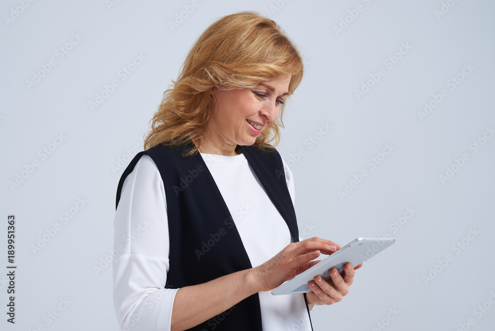 Side view of smiley mature blond with tablet pc