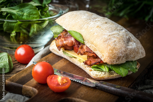 Tableau sur toile Ciabatta sandwich with arugula salad, bacon and yellow cheese.