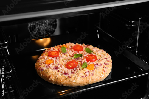 Tasty pizza on baking sheet in oven