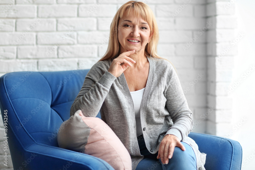 Happy mature woman relaxing in armchair at home Happy mature woman relaxing in armchair at home