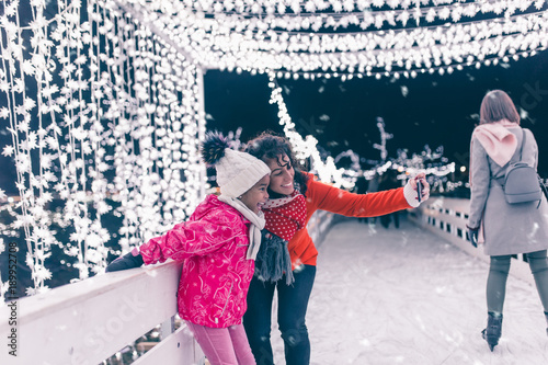 Cute black girl taking selfie photo with her mother at ice skating.