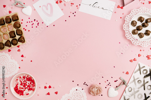 Valentine's Day concept. Frame of heart symbols, accessories, sweets, postcards on pink background. Flat lay, top view.
