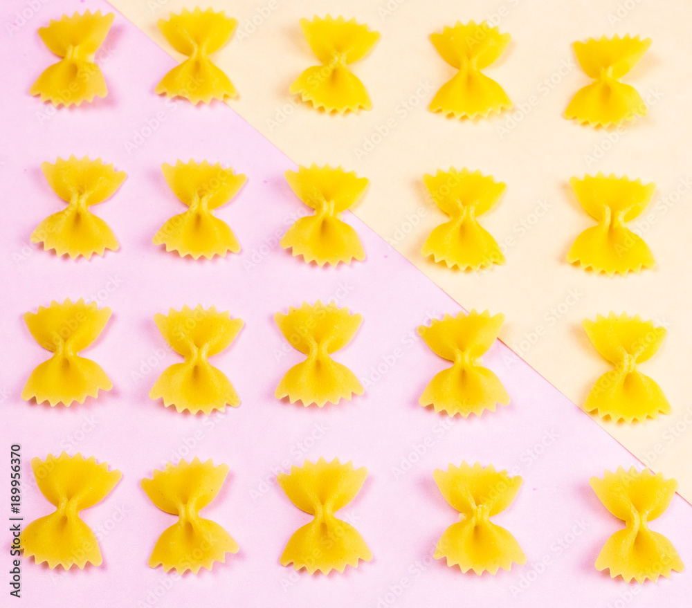 Fototapeta premium Yellow pasta on pastel pink background close up macro.