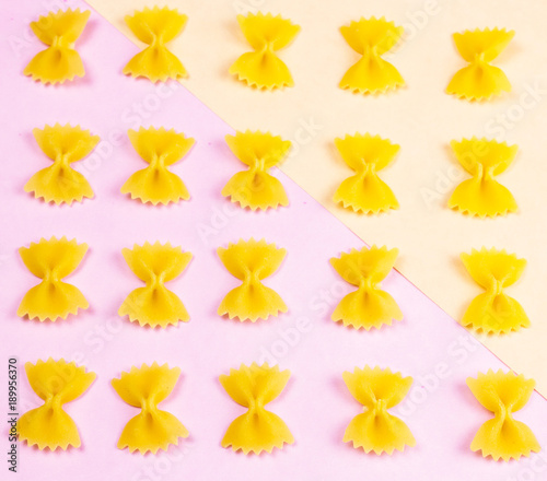 Yellow pasta on pastel pink background close up macro.