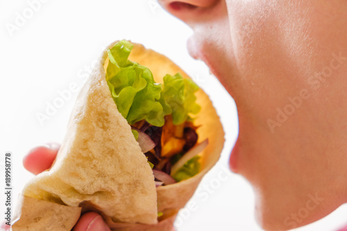 Eating Mexican burrito in hand with chicken, pepper and beans photo