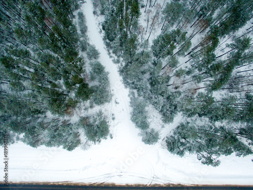 Winter forest and road. View from above. The photo was taken with a drone. Pine and spruce forest with a road in the snow