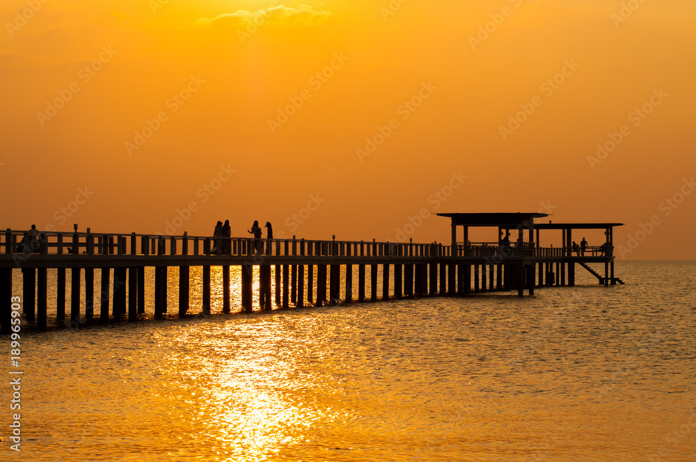 Silhouette of wooden bridge at sunset.