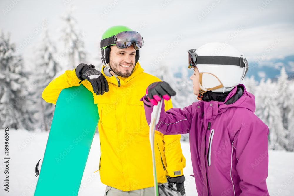 Young couple in winter sports clothes talking together standing with snowboards during the winter vacation on the snowy mountains