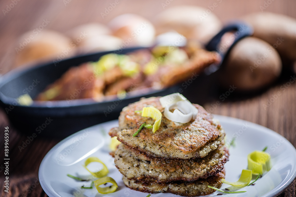stacked fried potato cakes on white plate with sour cream, spring onion and chives stacked fried potato cakes on white plate with sour cream, spring onion and chives