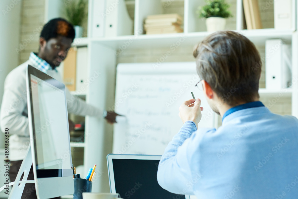 Portrait of two people, one of them African, brainstorming over business project while working in modern office, copy space