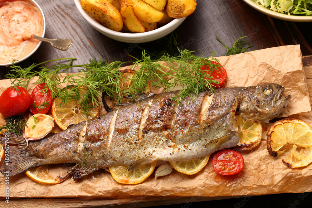 grilled fish with potatoes on wooden background grilled fish with potatoes on wooden background