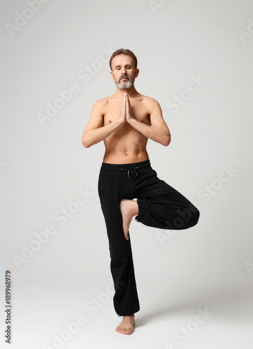 Old man practicing yoga doing stretching exercises