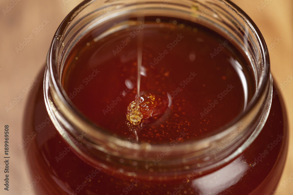 organic honey drips from wooden dipper in jar organic honey drips from wooden dipper in jar