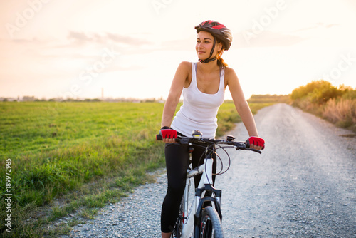 smiling girl on a bicycle outside the city at sunset photo