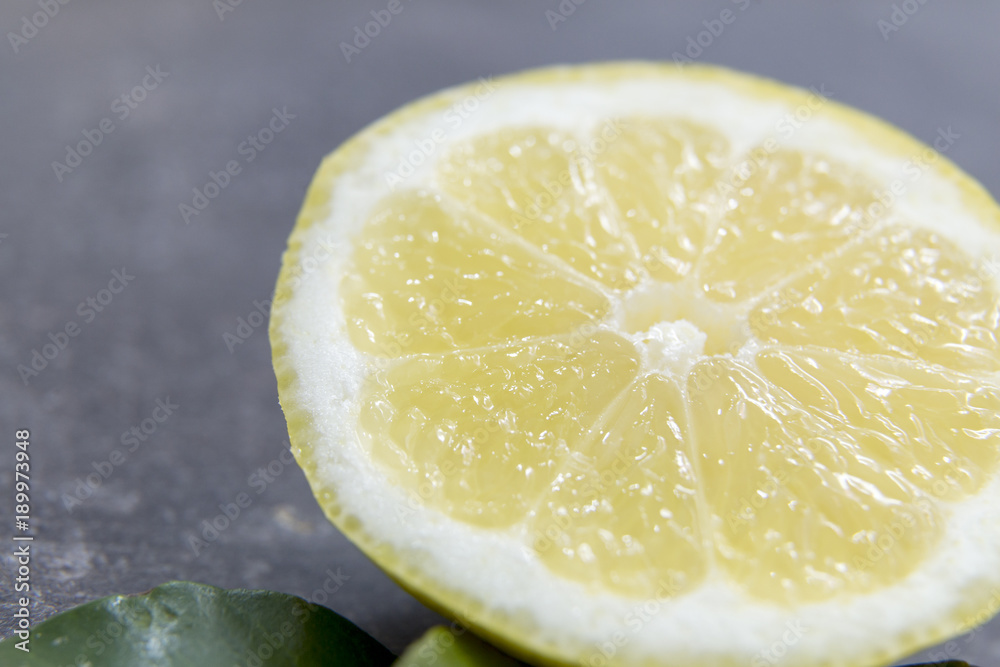 Sliced lemon with leaves on grey background Sliced lemon with leaves on grey background