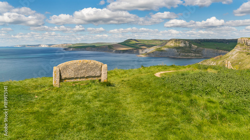 Stone bench at the South West Coast Path with a view over the Jurassic Coast and Emmett's Hill, near Worth Matravers, Jurassic Coast, Dorset, UK photo
