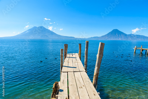 Wooden pier at Lake Atitlan on the beach in Panajachel, Guatemala. With beautiful landscape scenery of volcanoes Toliman, Atitlan and San Pedro in the background. Volcano Highland in Central America. photo