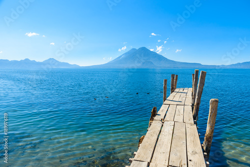 Wooden pier at Lake Atitlan on the beach in Panajachel, Guatemala. With beautiful landscape scenery of volcanoes Toliman, Atitlan and San Pedro in the background. Volcano Highland in Central America. © Simon Dannhauer
