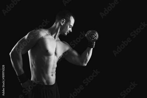 Strong athletic man with dumbbell showes naked muscular body © Prostock-studio