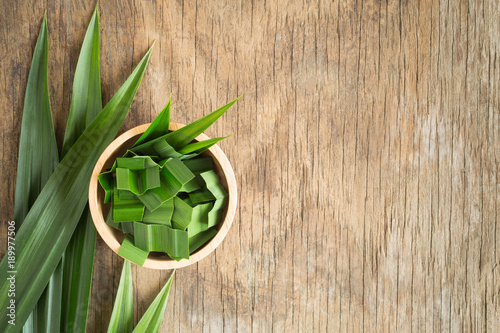 Fresh green pandan in a wooden bowl on wood table,pandan leaves on old wood background,top view and copy space photo