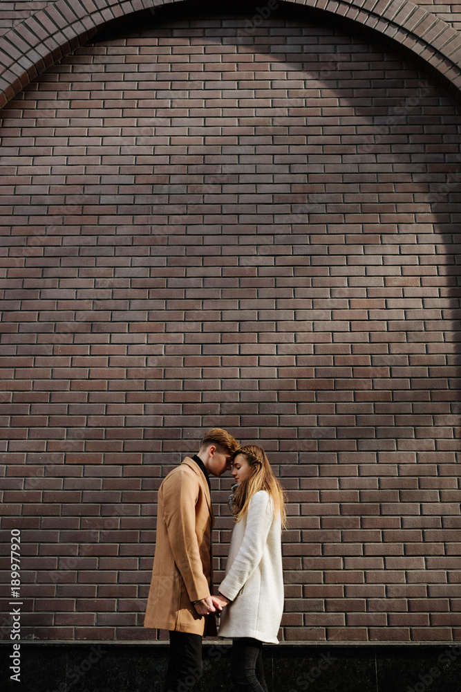 Love and dating. Young couple hold hands. Romantic relationship and happiness. Brick wall copy space background