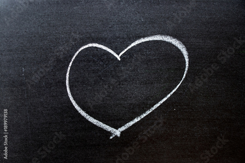 White coloe chalk drawing as heart shape on blackboard background with copy space photo