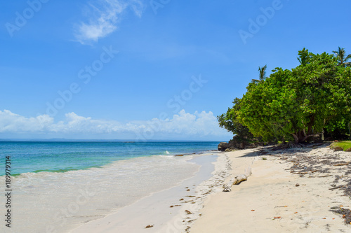 Weißer Sandstrand mit Bäumen auf einer tropischen Insel, strahlend blauer Himmel, Dominikanische Republik, Wellen am Strand, türkisfarbenes blaues Meer