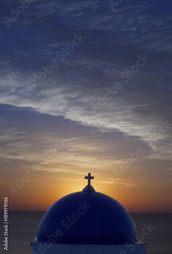 Santorini sunrise over the blue dome of a church near Pori Oia on the Greek Island of Santorini Greece