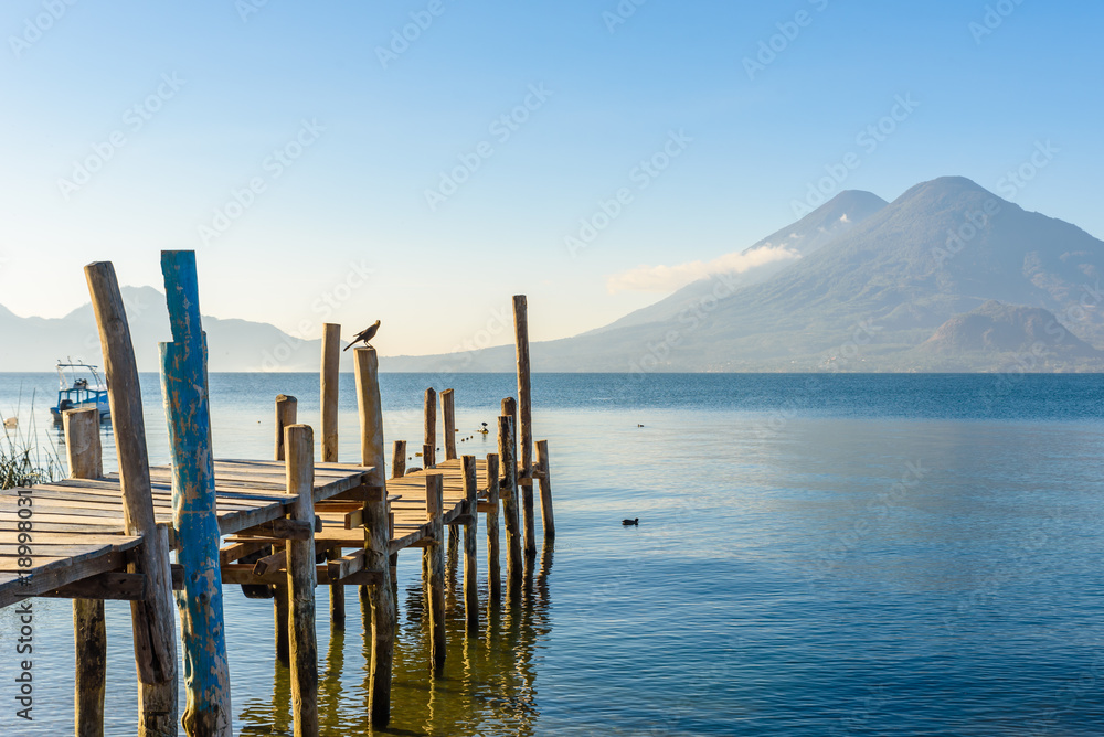 Wooden pier at Lake Atitlan on the beach in Panajachel, Guatemala. With beautiful landscape scenery of volcanoes Toliman, Atitlan and San Pedro in the background. Volcano Highland in Central America.