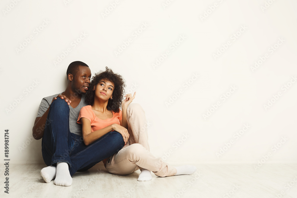 African-american couple looking up, sitting on floor African-american couple looking up, sitting on floor