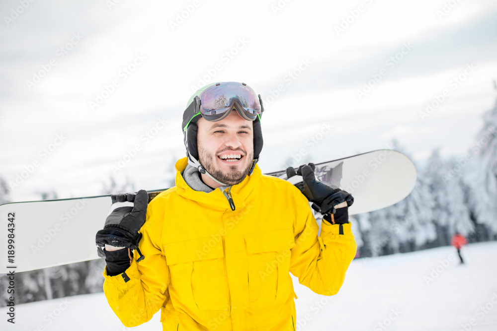 Portrait of a man in winter sports clothes walking with snowboard outdoors