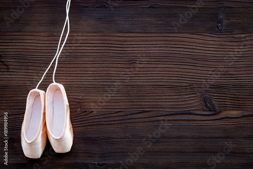 Ballet pointe shoes on dark wooden background top view copy space