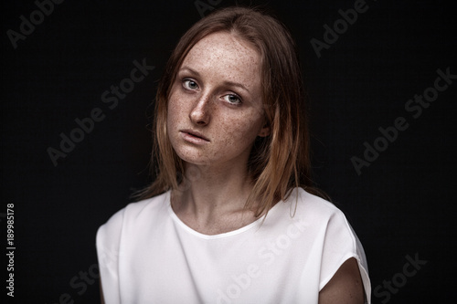 closeup studio portrait of freckled woman without makeup