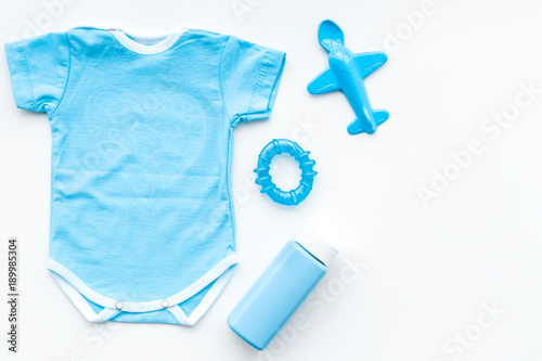Blue baby clothes for little boy. Bodysuit, toys, cosmetics on white background top view copy space