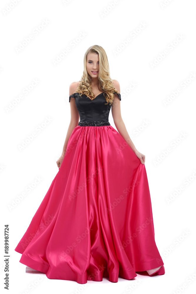 Wonderful girl wearing amazing long pink and black evening dress. Good choice for prom. Girl is very beatiful and has blonde curly hair, nice light make-up. Photo was taken on white studio background.