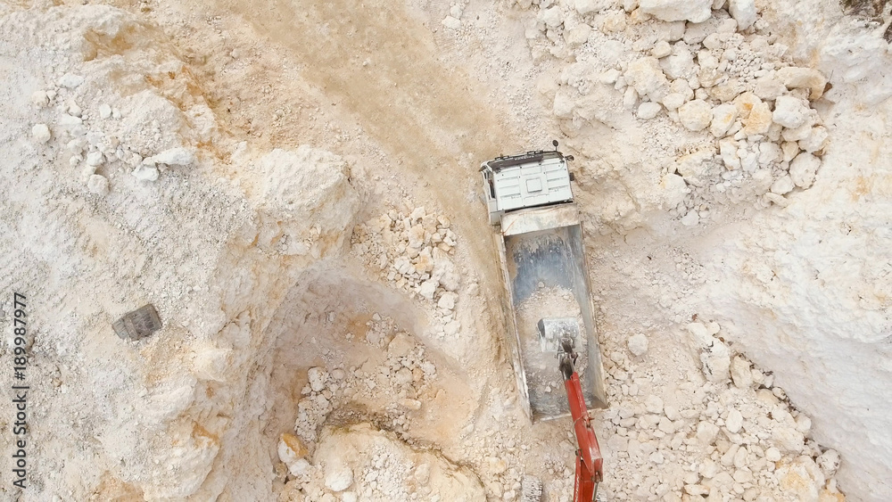 Excavator loads the truck in a limestone quarry. Aerial view wheel