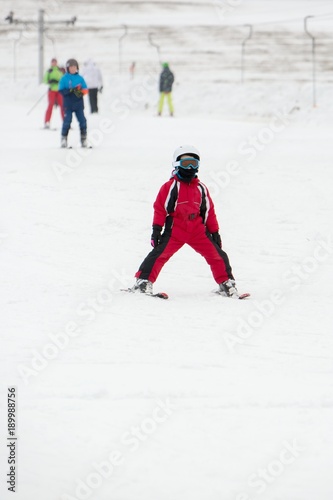 Small boy in ski mask and helmet learns skiing
