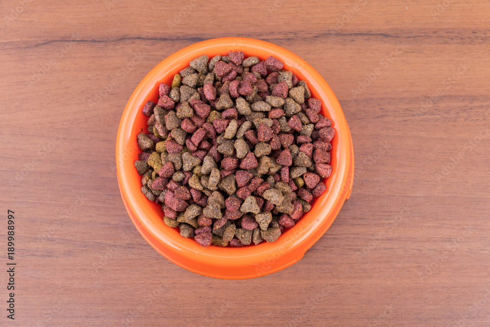 Dry cat food in bowl on wooden background. Pet food on wood surface. Top view Dry cat food in bowl on wooden background. Pet food on wood surface. Top view