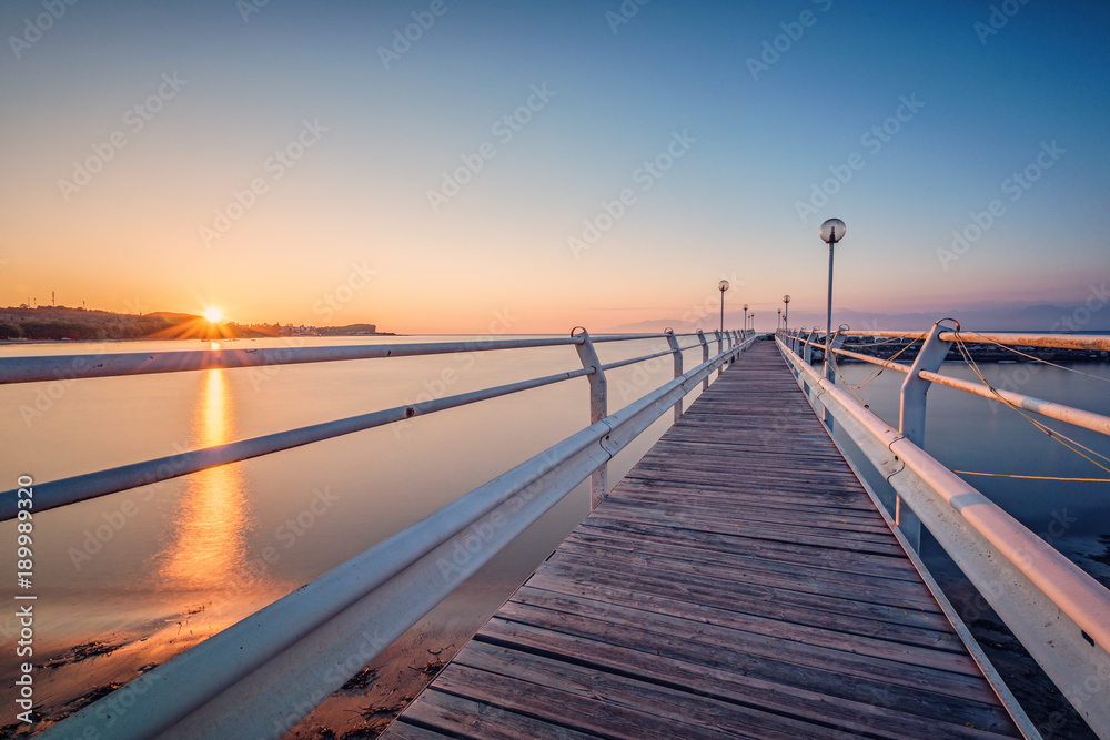 Wooden pier at sunset time on Corfu island. Roda village. Greece.