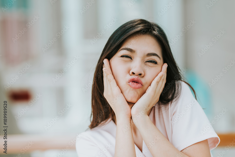 Asian woman making funny face expression with hands cover her cheek indoor Asian woman making funny face expression with hands cover her cheek indoor